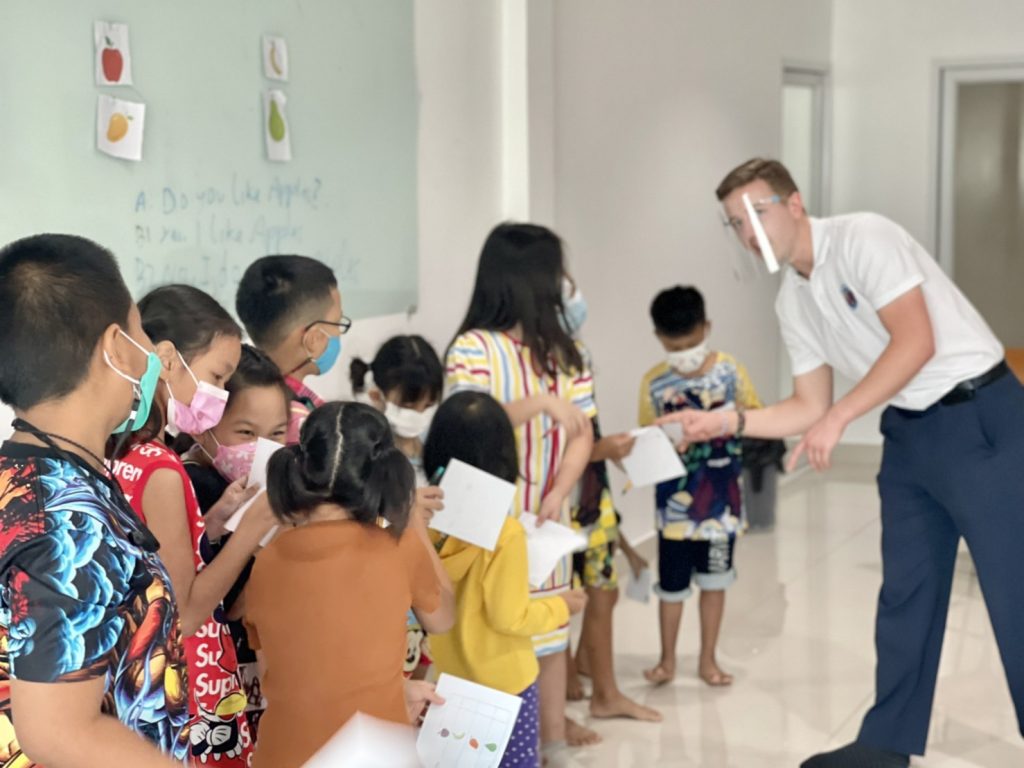 Teacher lines up students for high fives while teaching abroad in Thailand